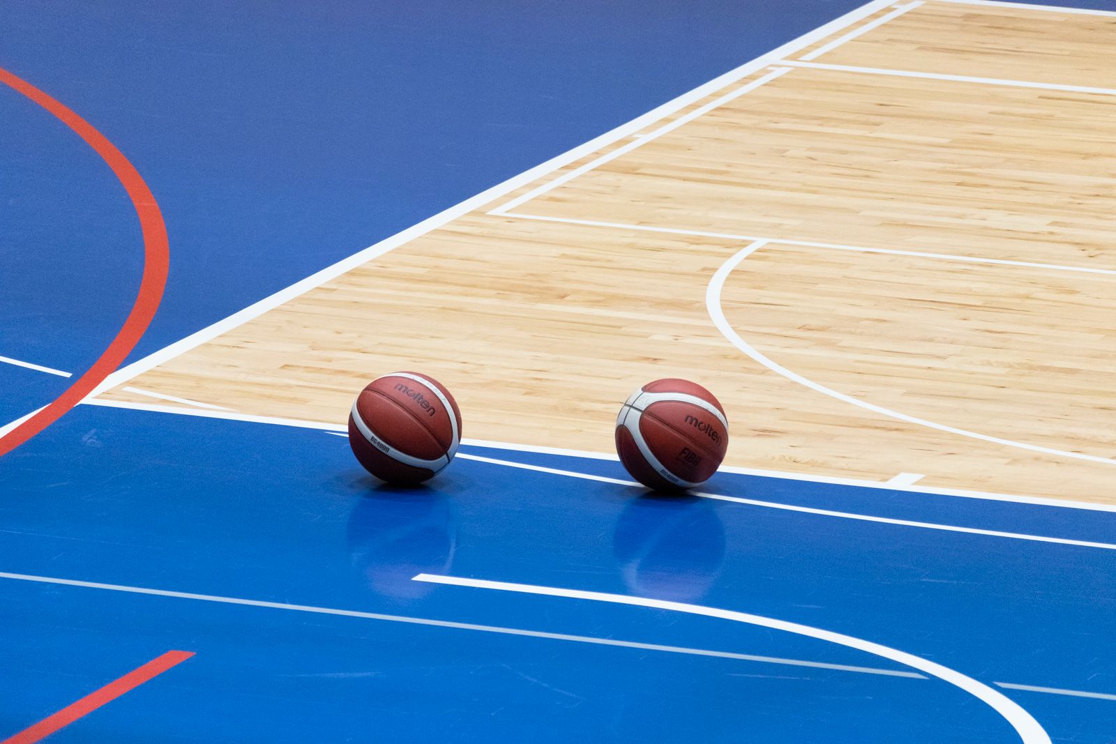 Basketballs resting on a blue indoor court