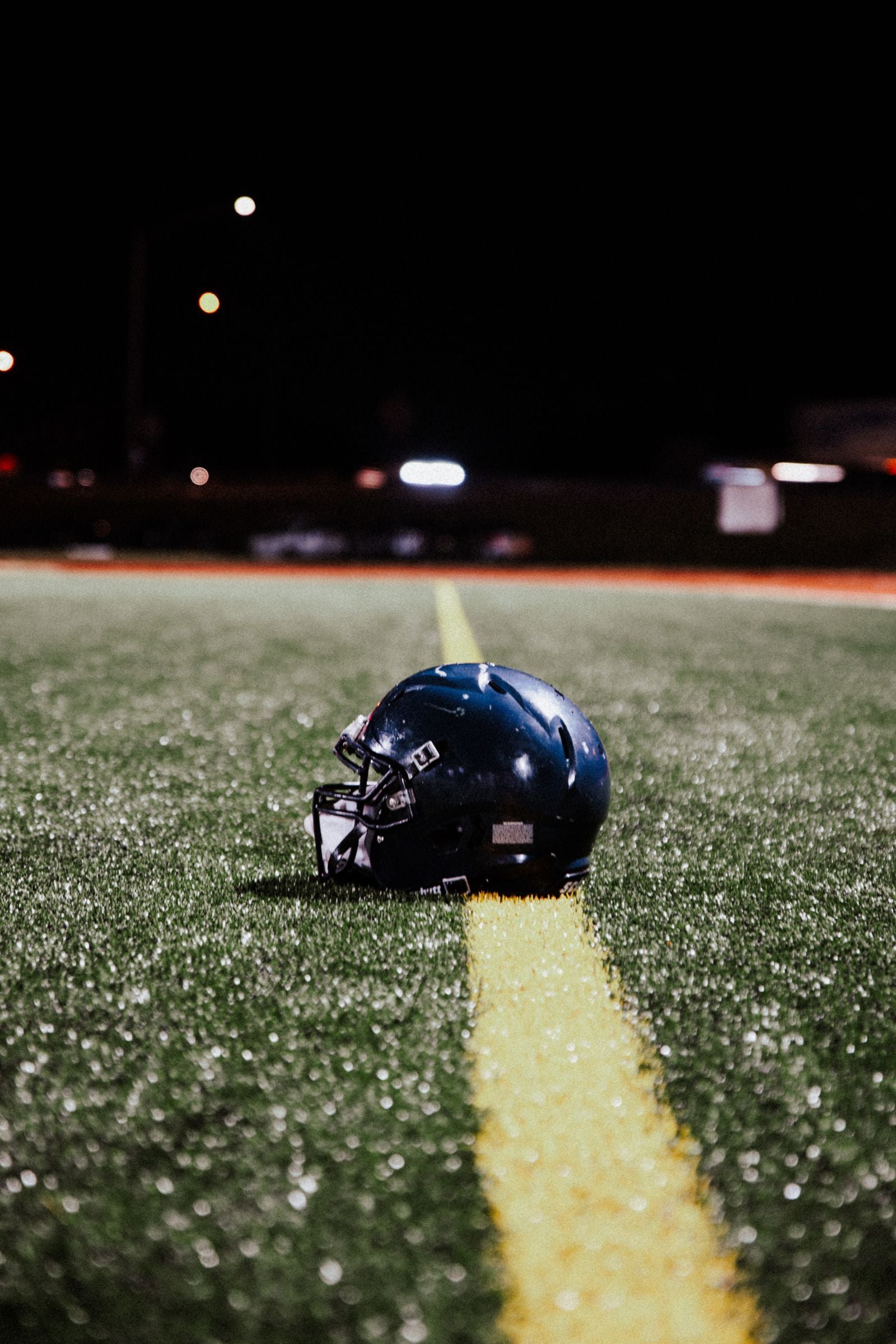 Football helmet resting on the field under stadium lights
